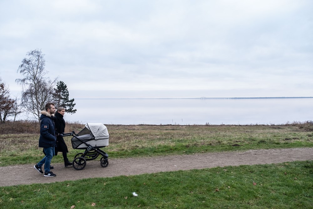 Par går tur med barnevogn langs havet